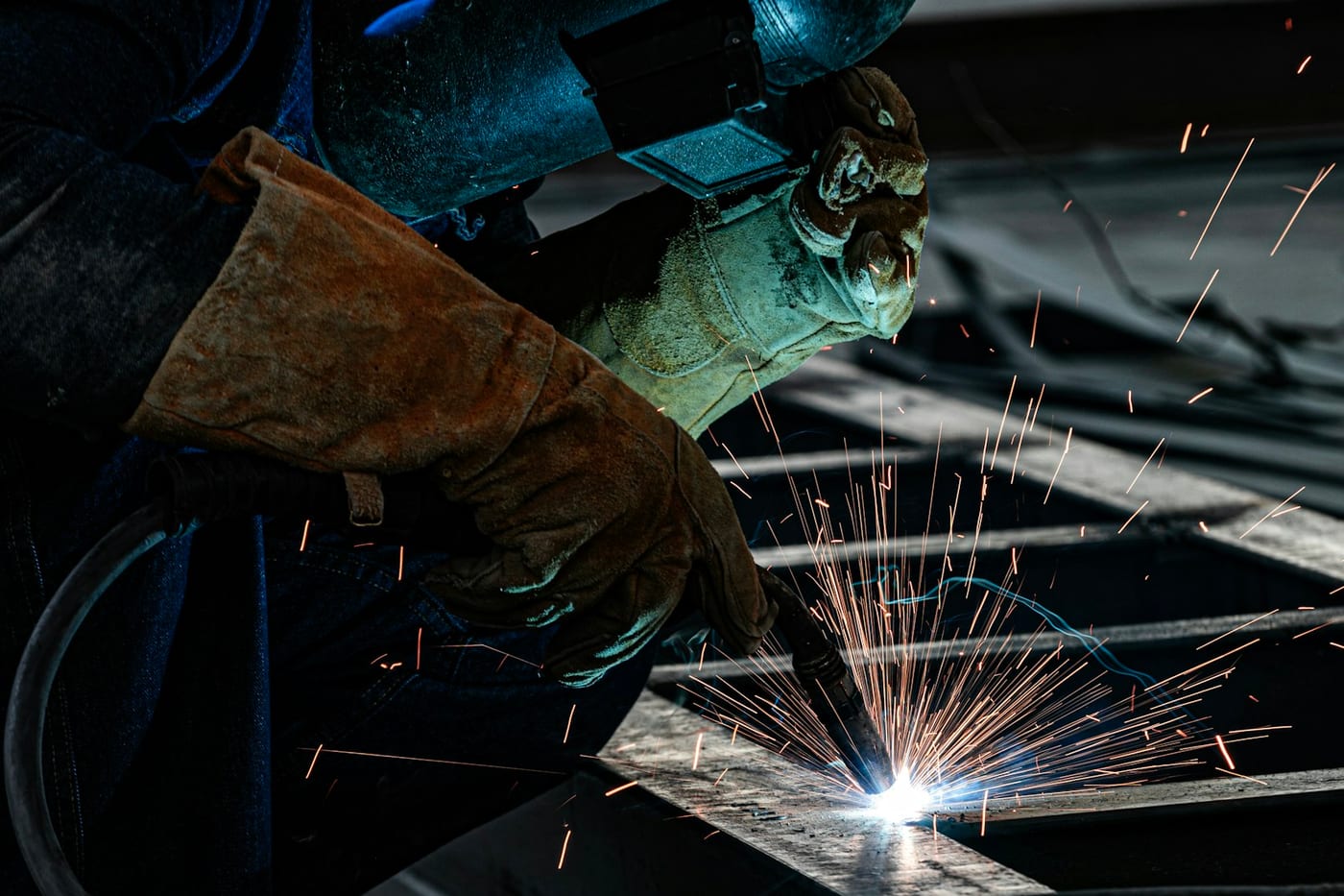 Welder laying a bead with sparks in a fabrication shop